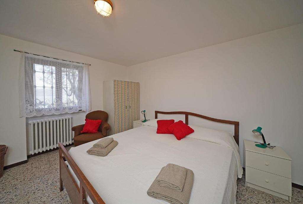 une chambre avec un grand lit blanc avec des oreillers rouges dans l'établissement Ville in uliveto vista lago - VILLA CASALIVA, à Pulciano 30 autres photos