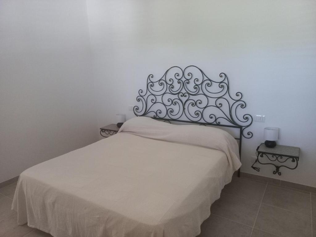 - une chambre avec un lit blanc et une tête de lit en métal dans l'établissement Villa Molillo, à Ostuni