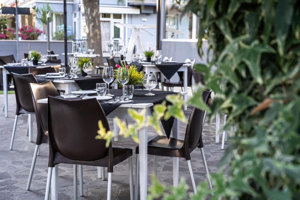 un restaurant avec des tables et des chaises avec des fleurs dessus dans l'établissement HOTEL OLIVER, à Cervia 33 autres photos