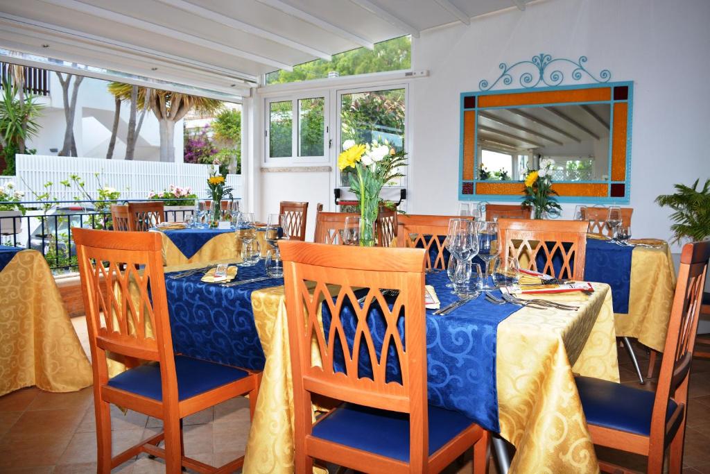 une salle à manger avec des tables et des chaises bleues et jaunes dans l'établissement Hotel Ristorante Mediterraneo Faro, à San Vito Lo Capo