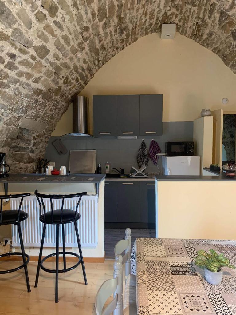 une cuisine avec une table et des chaises dans une pièce dans l'établissement Le gîte vouté confort et repos, à Saint-Beauzély