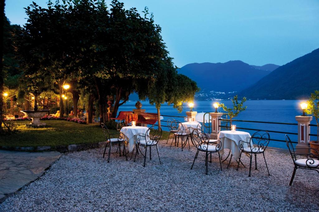 un groupe de tables et de chaises à côté de l'eau la nuit dans l'établissement Hotel Stella D'Italia, à Valsolda