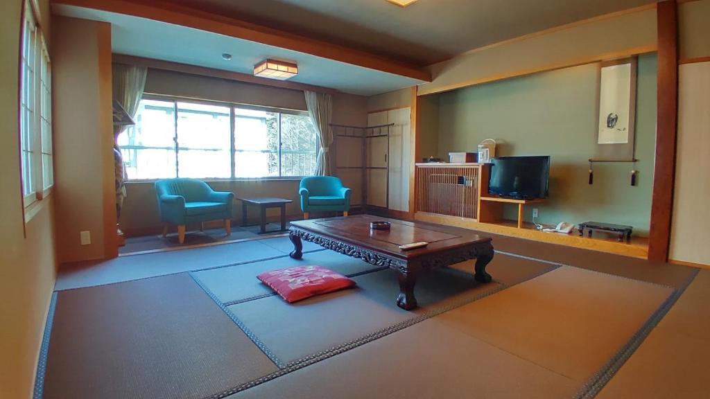 un salon avec une table et une télévision dans l'établissement Nasushiobara Masudaya, à Shiobara-machi