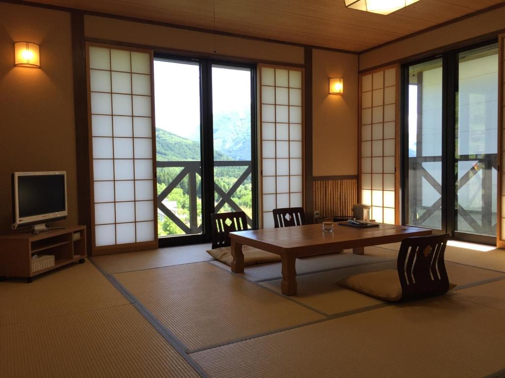 Cette chambre comprend une table, une télévision et des fenêtres. dans l'établissement Yufuin Tsubaki, à Yufu 16 autres photos