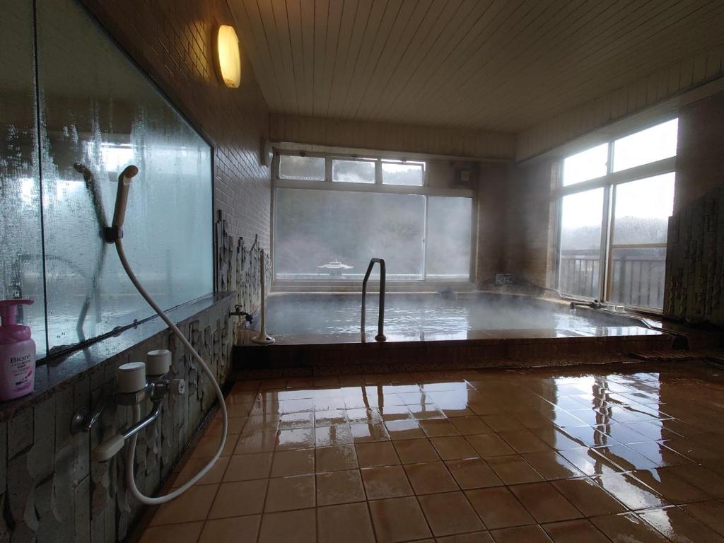 une salle de bain avec une baignoire avec douche et un lavabo dans l'établissement Nasushiobara Masudaya, à Shiobara-machi