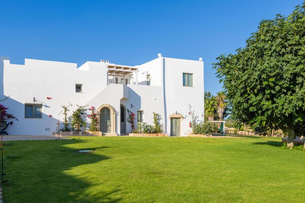 une grande maison blanche avec une cour verte dans l'établissement Masseria Baroni di Montesardo, à Lido Marini