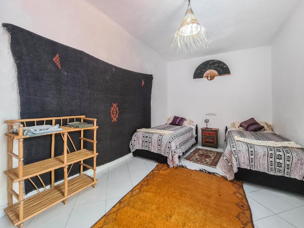 - une chambre avec 2 lits et une étagère dans l'établissement Riad MIYA, à Essaouira