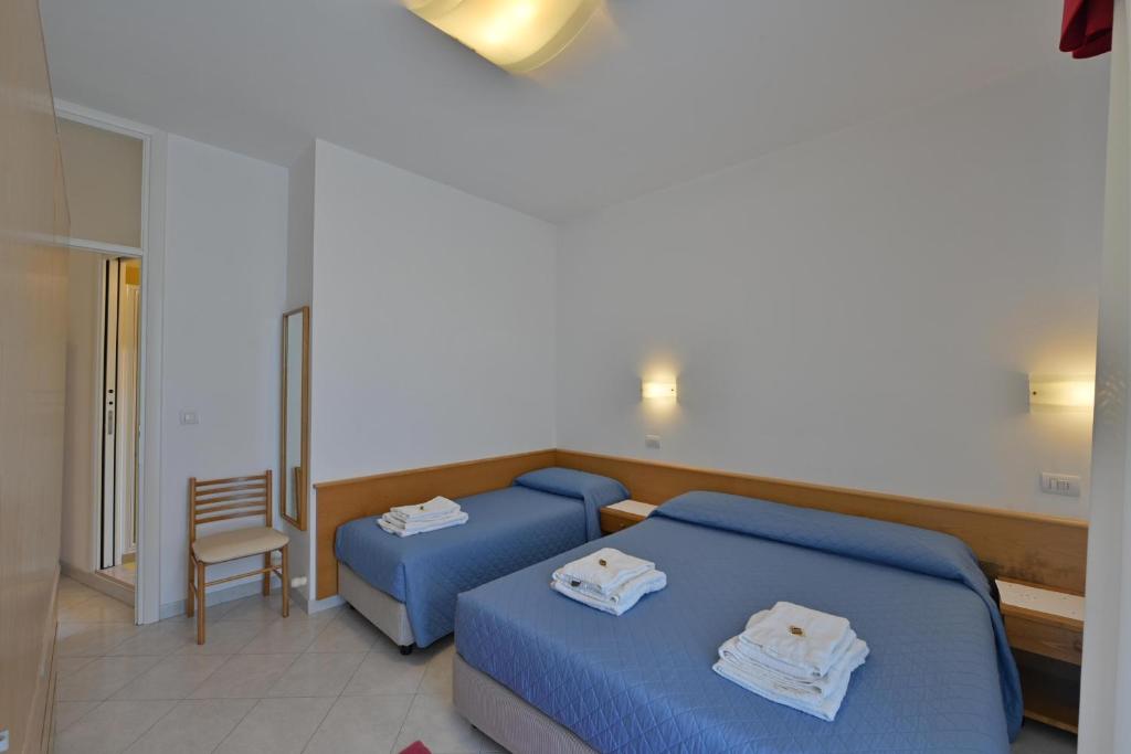 une chambre d'hôtel avec deux lits et une chaise dans l'établissement Residence Mariavittoria, à Lido di Jesolo