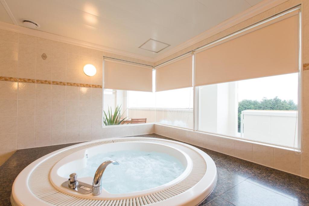 une baignoire dans une salle de bain avec une grande fenêtre dans l'établissement ホテルシエル沼津店 沼津インター -大人専用-, à Numazu