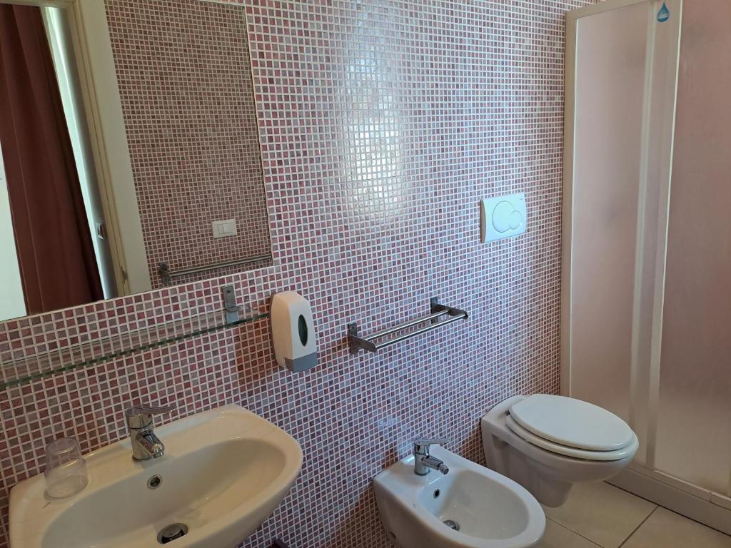 une salle de bain avec un lavabo, des toilettes et un miroir dans l'établissement Hotel La Punta, à Otrante