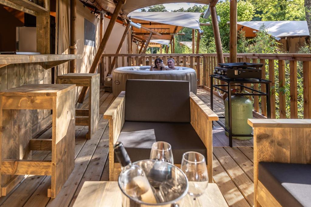 un patio avec une table et des chaises sur une terrasse dans l'établissement Aloha plage camping 4étoiles, à Sampzon