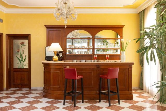 - un bar avec deux tabourets rouges dans une pièce dans l'établissement Hotel Villa Cipro, sur le Lido de Venise