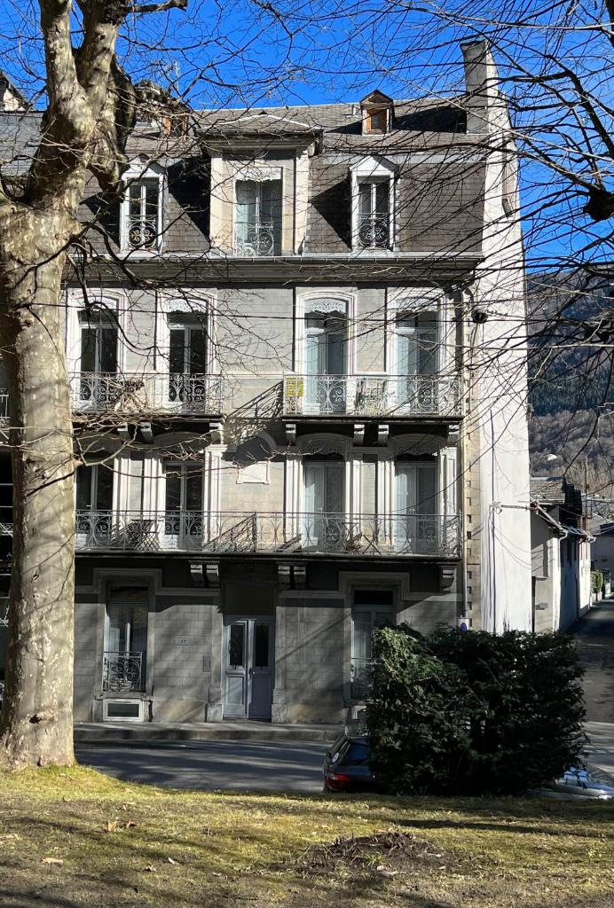 un grand bâtiment blanc avec un arbre devant dans l'établissement Fantastic Ground Floor Apartment Opposite Thermes, à Luchon