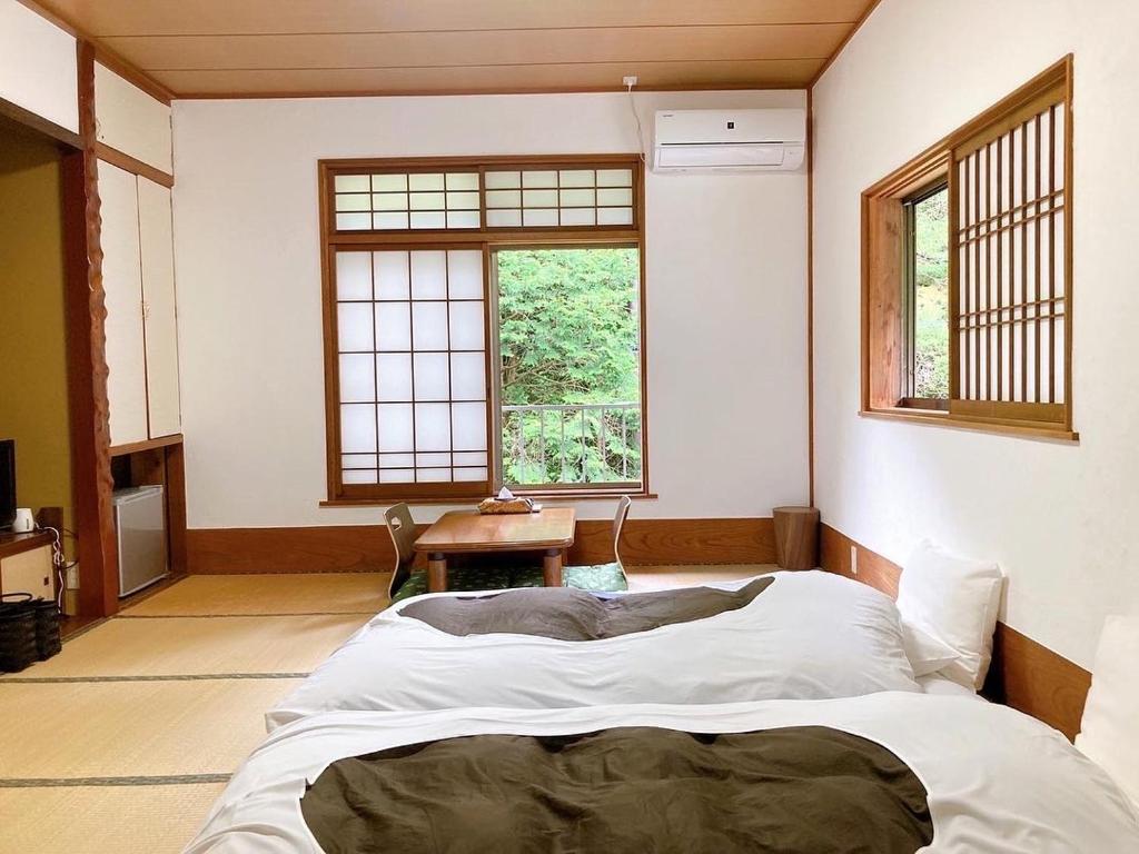 - une chambre avec un grand lit dans une pièce dotée de fenêtres dans l'établissement YUPOPPO Hakone, à Hakone