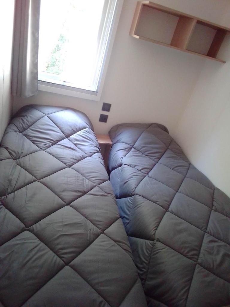 un lit dans une petite pièce avec une fenêtre dans l'établissement Mobil home Neuf 6 places Climatisé, à Camiers