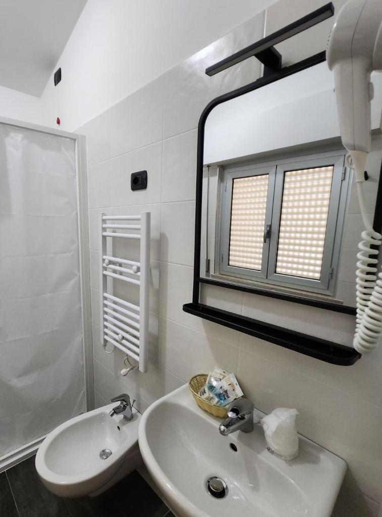 une salle de bain blanche avec un lavabo et un miroir dans l'établissement Hotel Miramare Dipendenza, à Pineto