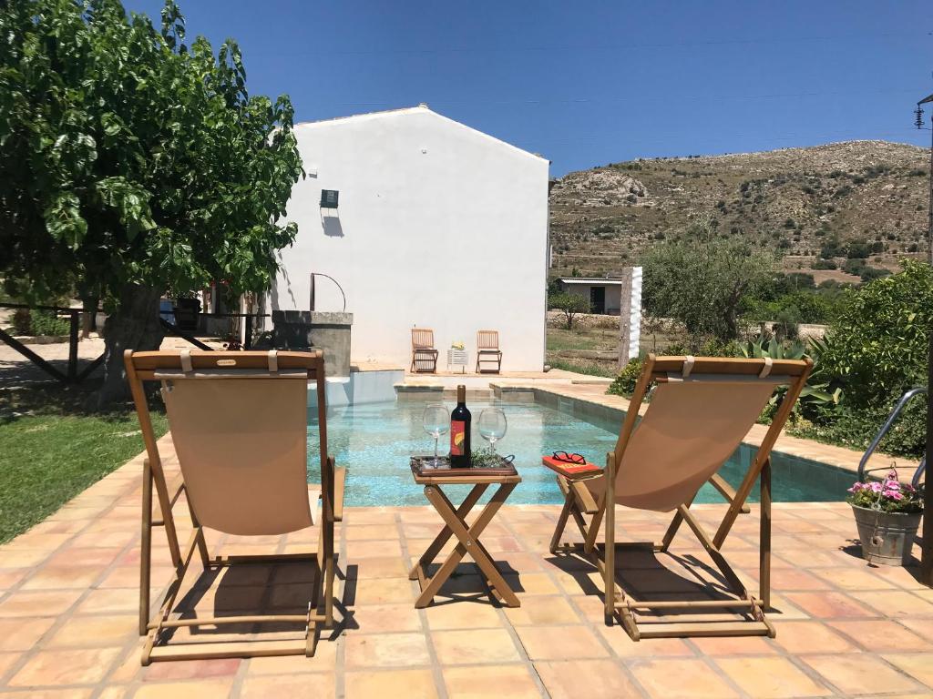 deux chaises et une table à côté d'une piscine dans l'établissement Authentic Sicilian Charm, pool, sea view, wi-fi & parking, à Avola
