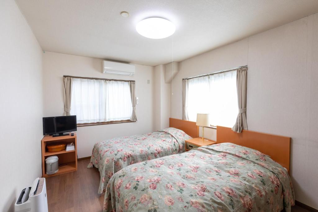 une chambre d'hôtel avec deux lits et une télévision dans l'établissement 天然温泉白川郷の湯, à Shirakawa-gō