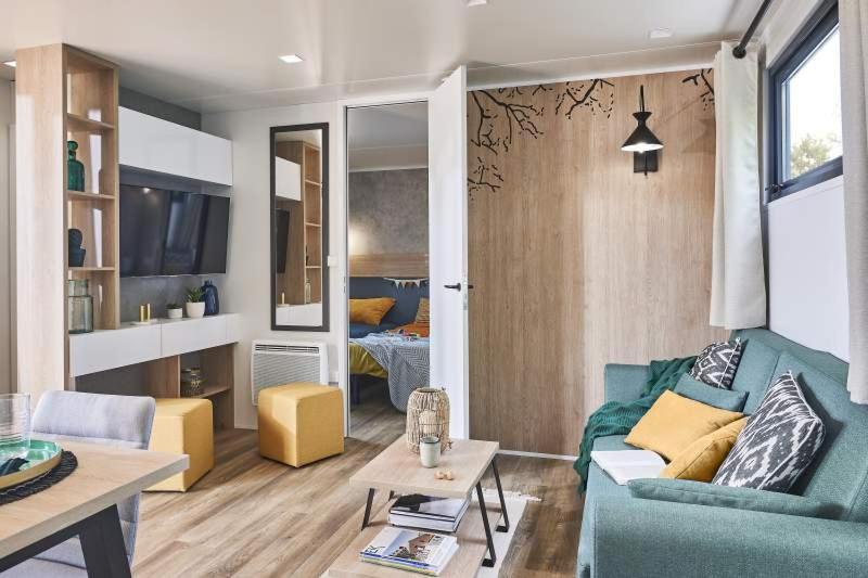 un salon avec un canapé bleu et une table dans l'établissement Camping Country Park Crecy La Chapelle - Site Officiel - Next to Disneyland Paris, à Crécy-la-Chapelle