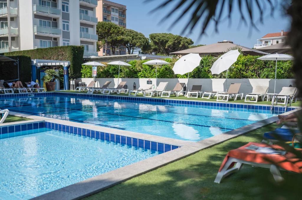 une grande piscine avec chaises et parasols dans l'établissement Hotel Excelsior, à Lido di Jesolo