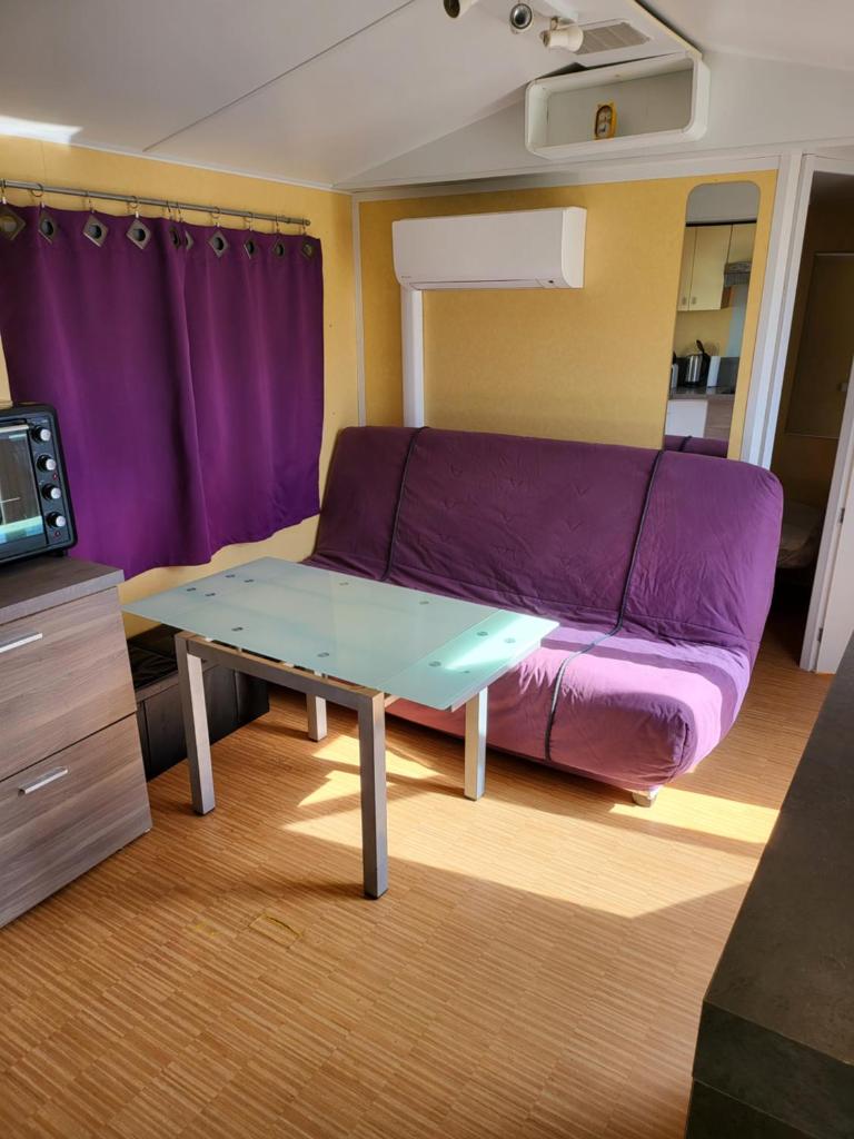 un salon avec un canapé violet et une table dans l'établissement Mobil home climatisé 6 personnes avec piscine, à Fréjus