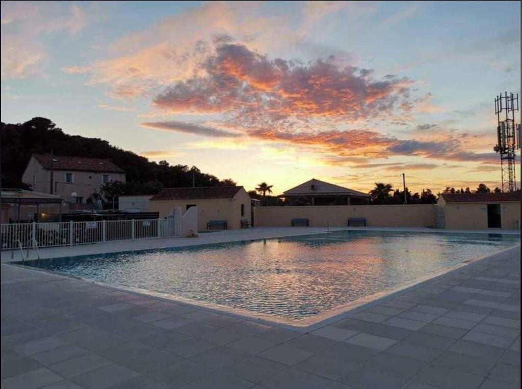 une grande piscine avec un coucher de soleil en arrière-plan dans l'établissement Mobil home climatisé 6 personnes avec piscine, à Fréjus