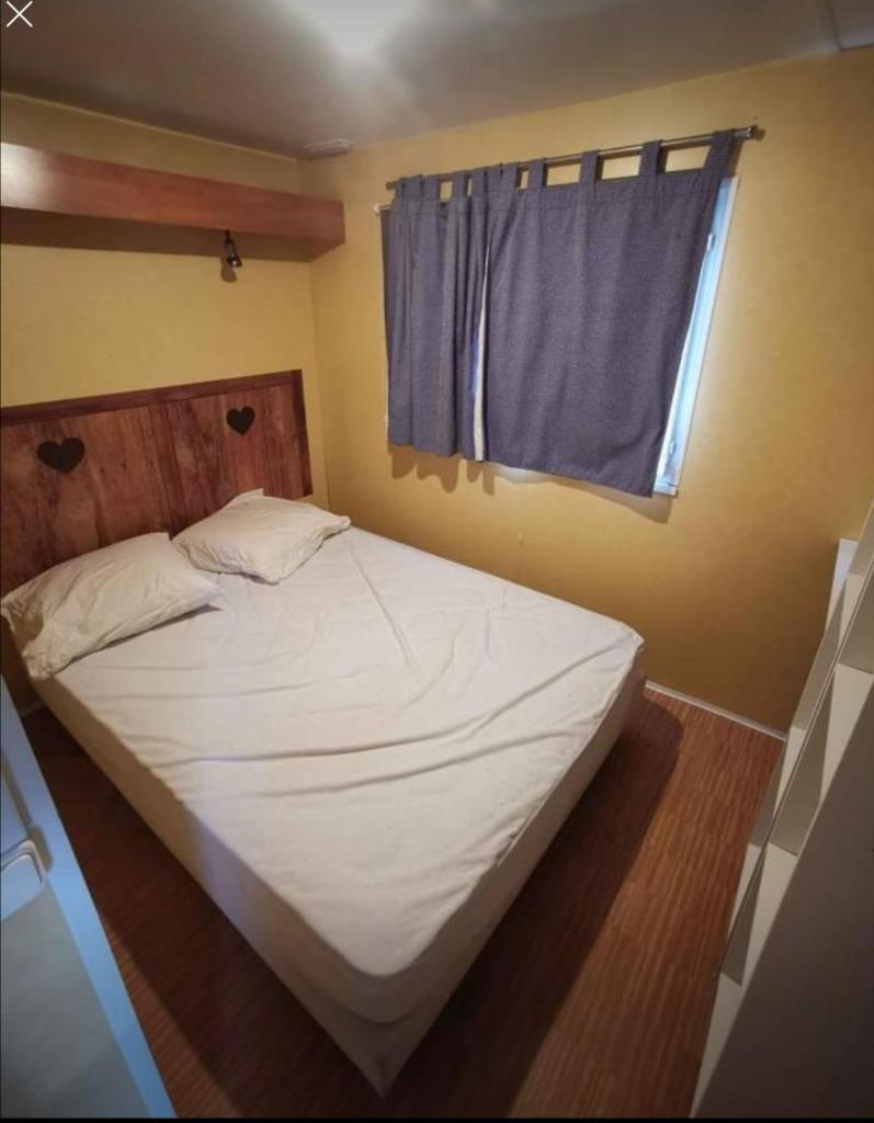 Ce lit se trouve dans un dortoir doté d'une fenêtre bleue. dans l'établissement Mobil home climatisé 6 personnes avec piscine, à Fréjus