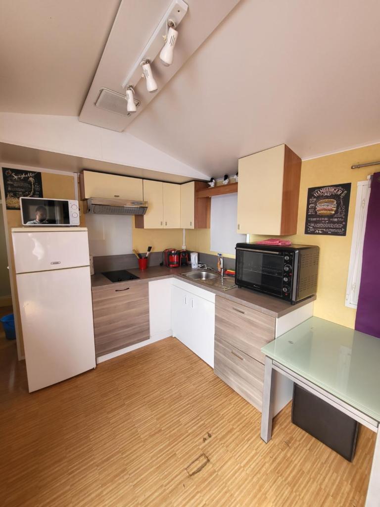 une cuisine avec des armoires blanches et une table en verre dans l'établissement Mobil home climatisé 6 personnes avec piscine, à Fréjus