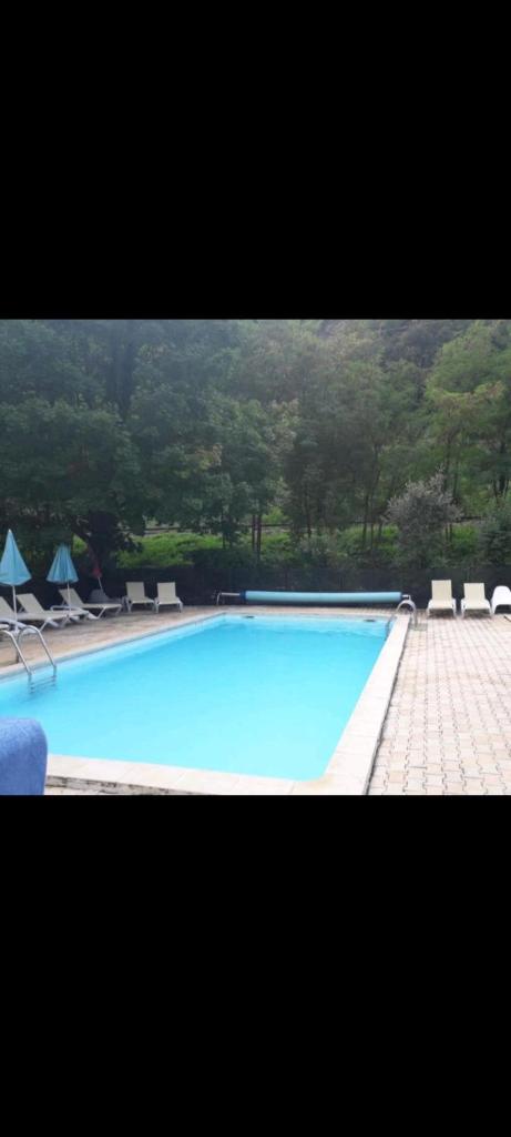 une grande piscine bleue avec chaises et parasols dans l'établissement Mobil home, à Villefranche-de-Conflent