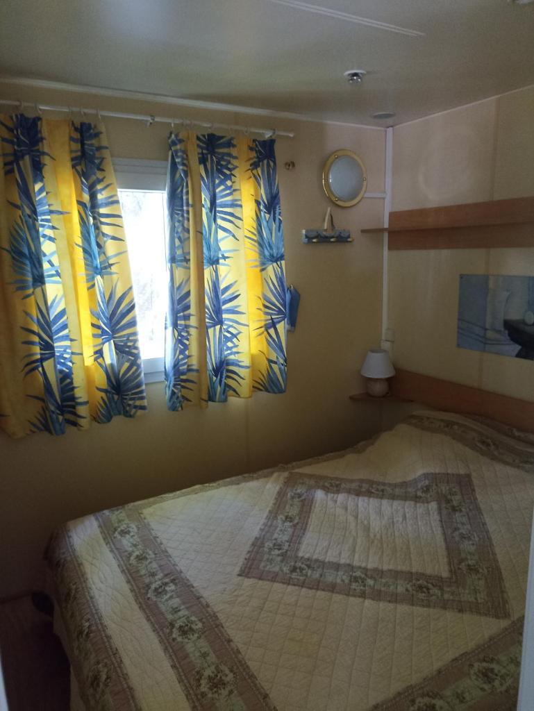 - une chambre avec un lit orné de rideaux jaunes et bleus dans l'établissement Mobil home, à Villefranche-de-Conflent 14 autres photos