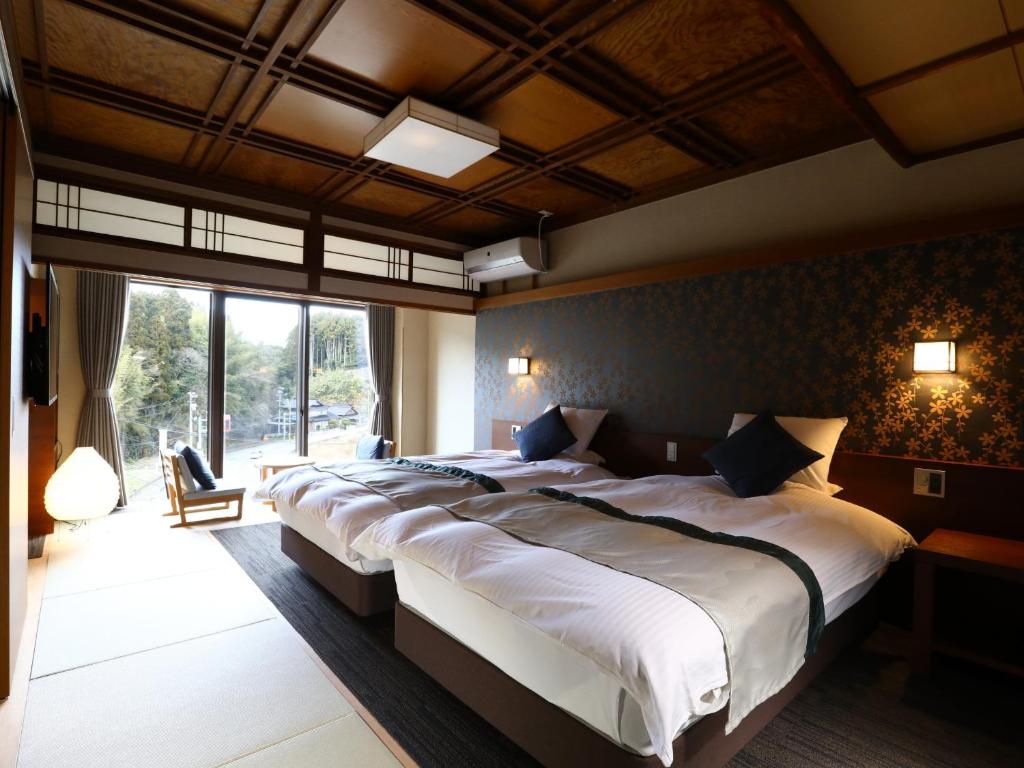 une chambre avec un grand lit et une grande fenêtre dans l'établissement Umiakari, à Himi