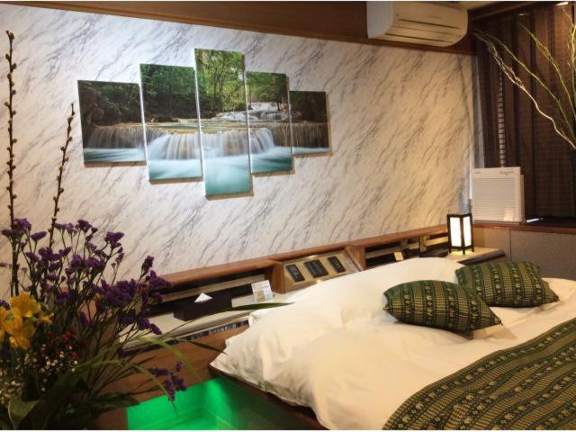 une chambre avec un lit et des tableaux au mur dans l'établissement HOTEL GEN 猪名川店, à Yamashita