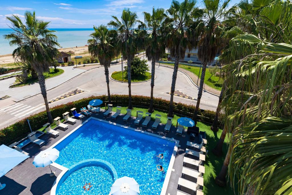 - une vue sur la piscine bordée de chaises et de palmiers dans l'établissement Kiara Residence, à Giulianova