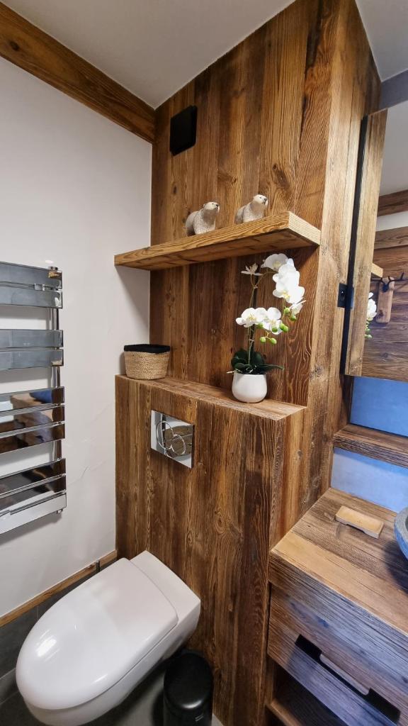 La salle de bains est pourvue d'un mur en bois et de toilettes. dans l'établissement Arcs 1950 Appartement Luxe type chalet 5 à 7 personnes Vue imprenable sur le Montblanc skis aux pieds, à Arc 1950