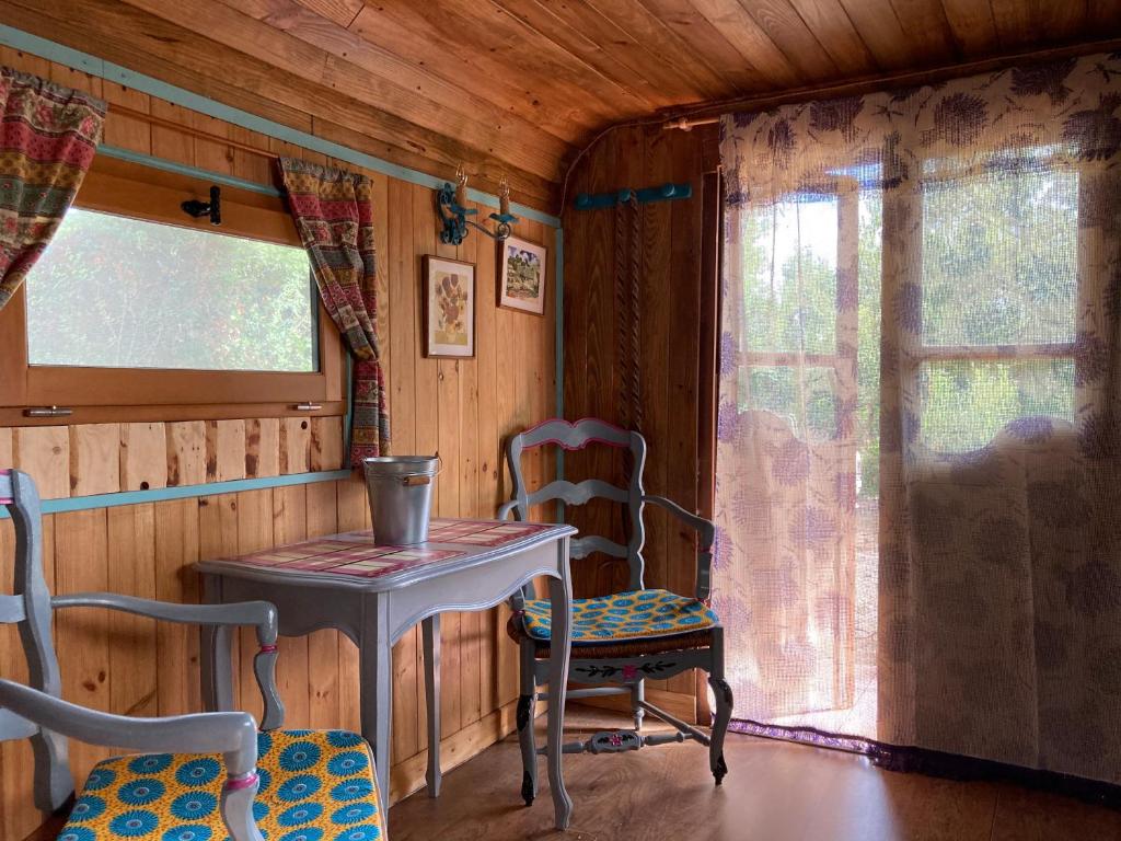 une table et des chaises dans une pièce avec une fenêtre dans l'établissement Authentique roulotte en Camargue, à Arles