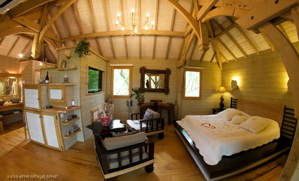 une chambre avec un grand lit dans une pièce avec des plafonds en bois dans l'établissement Cabane d'Amour, à Béziers