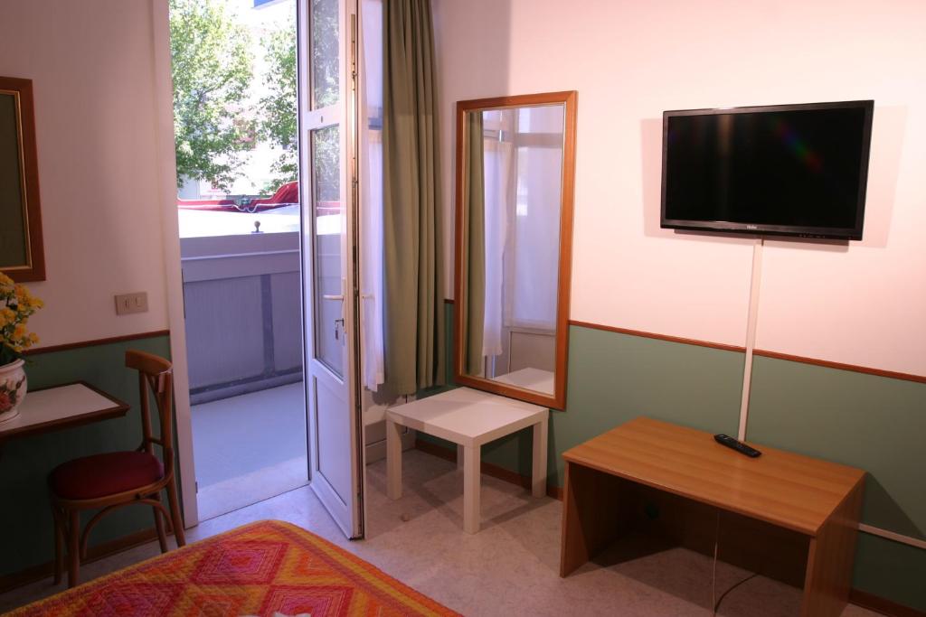 - un salon avec une télévision, une table et un miroir dans l'établissement Villa Romana, à Lignano Sabbiadoro