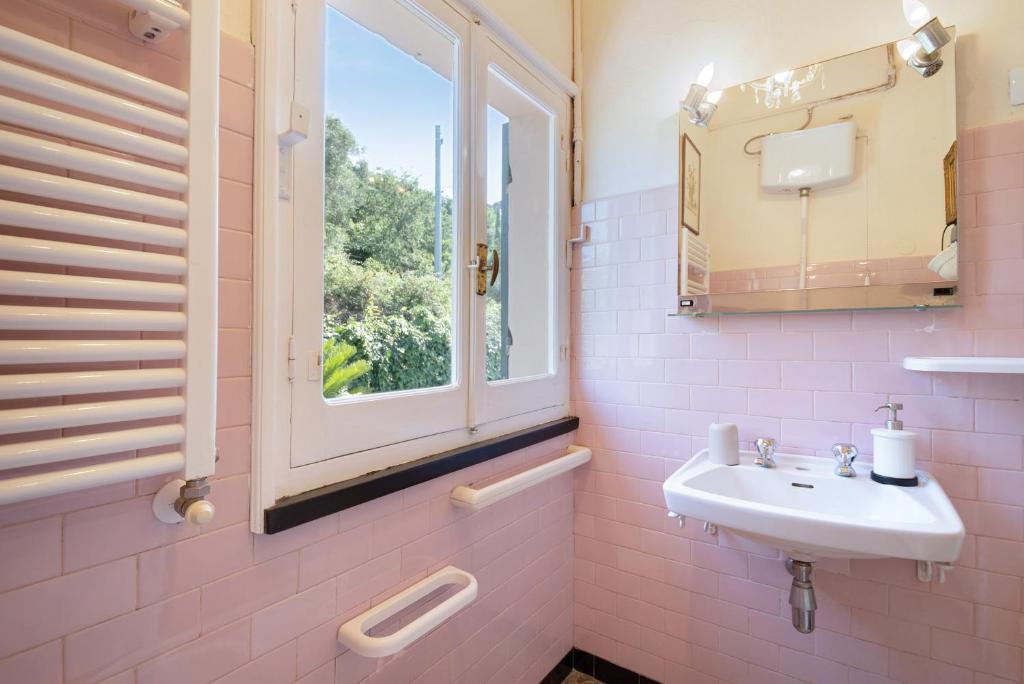 une salle de bains rose avec lavabo et fenêtre dans l'établissement Villa Mesco, à Levanto 24 autres photos