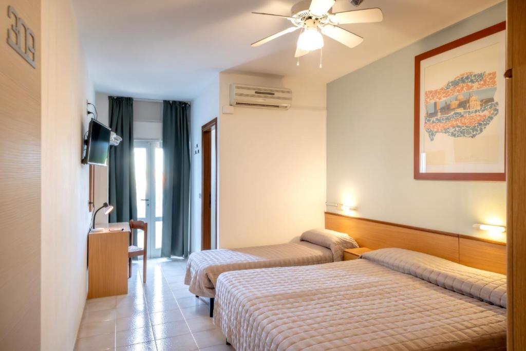 Cette chambre comprend deux lits et un ventilateur de plafond. dans l'établissement Hotel Itta, à Caorle