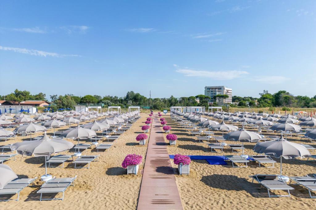une rangée de chaises longues et de parasols sur une plage dans l'établissement Laguna Park Hotel 4Superior, à Bibione
