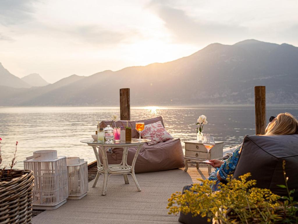 une femme assise sur un pont qui regarde l'eau dans l'établissement La Caletta Hotel Bolognese, à Brenzone