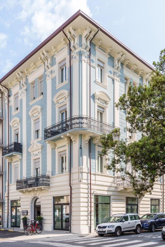un bâtiment bleu et blanc avec des voitures garées devant dans l'établissement Vi Suites, à Viareggio