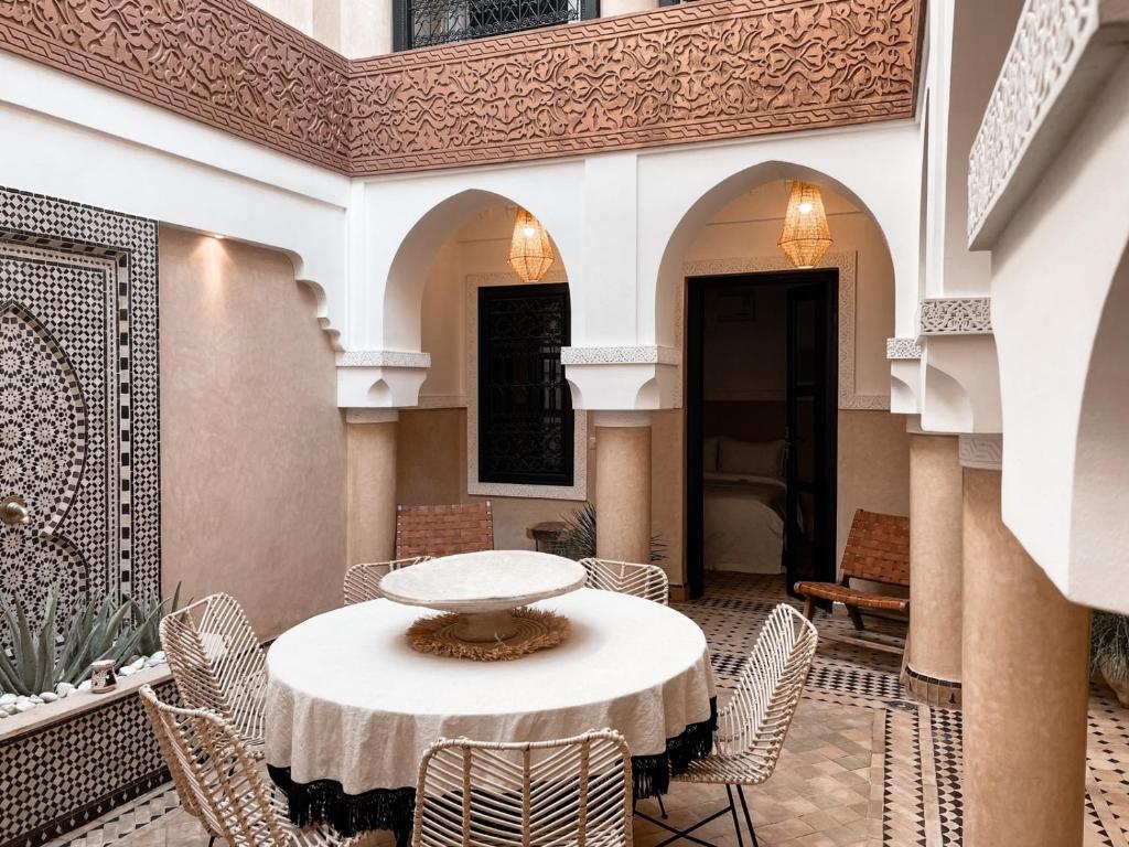 une cour avec une table et des chaises dans un bâtiment dans l'établissement Riad Comme chez soi Marrakech by Louhou collection, à Marrakech