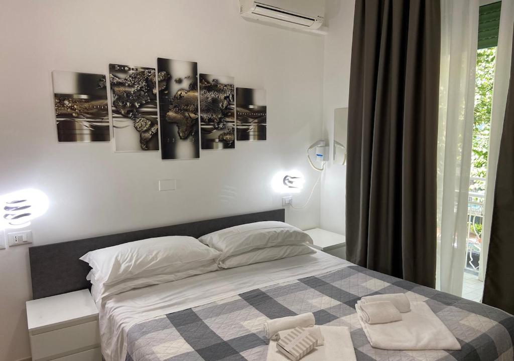 une chambre avec un lit avec quatre tableaux au mur dans l'établissement chiAma Hotel, à Rimini
