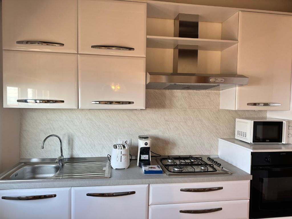 La cuisine est équipée de placards blancs, d'une cuisinière et d'un évier. dans l'établissement Piccadilly Penthouse with Jacuzzi, à Lido di Camaiore