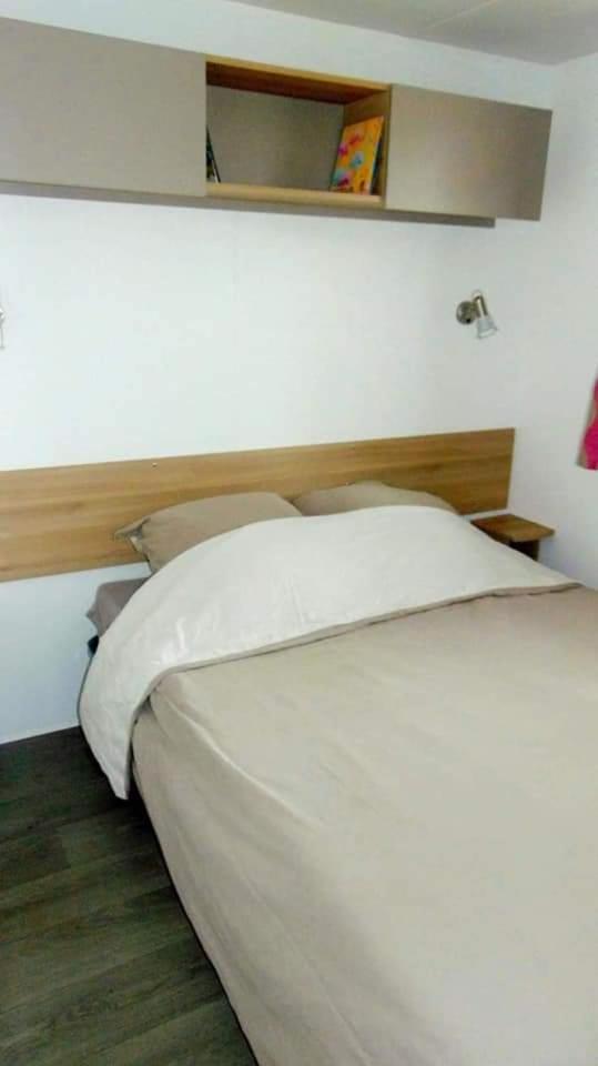 une chambre avec un lit blanc avec une tête de lit en bois dans l'établissement Mobilhome Canet-en-Roussillon, à Canet