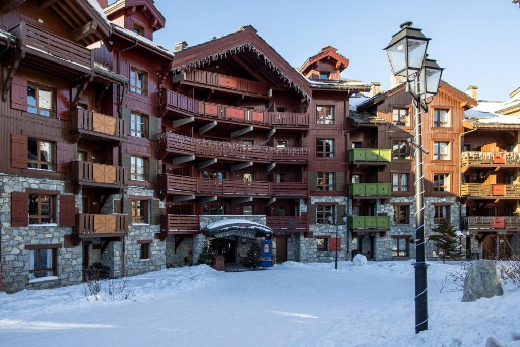 un grand bâtiment dans la neige avec un éclairage de rue dans l'établissement Arcs 1950 Appartement Luxe type chalet 5 à 7 personnes Vue imprenable sur le Montblanc skis aux pieds, à Arc 1950