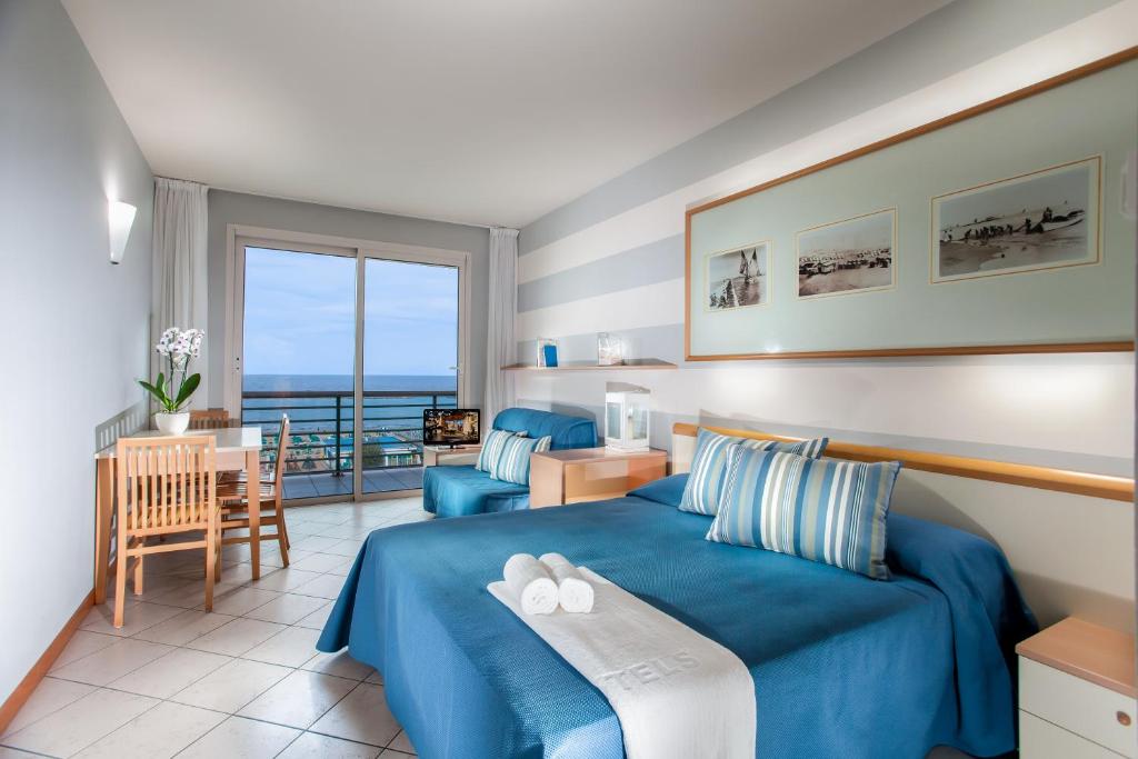 - une chambre avec un lit bleu, une table et des chaises dans l'établissement Hotel Valverde & Residenza, à Cesenatico