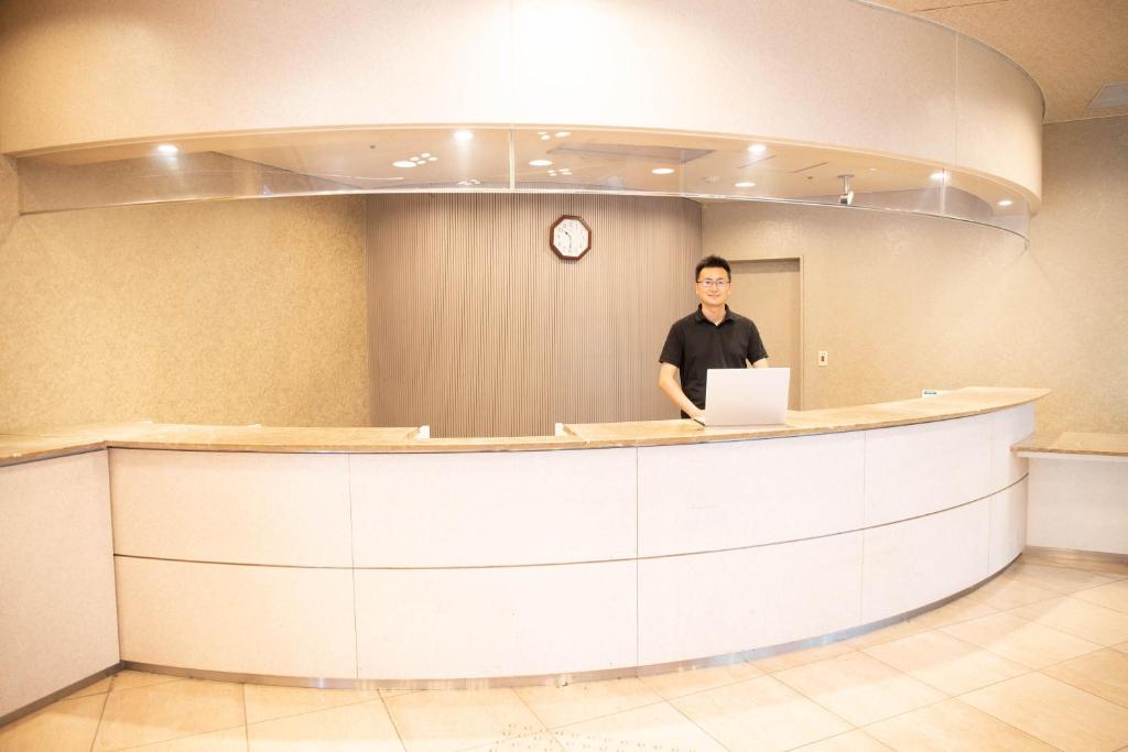 un homme debout à un comptoir avec un ordinateur portable dans l'établissement Bizan Kaigetsu, à Tokushima 9 autres photos
