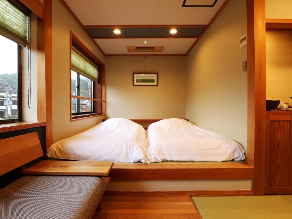 deux lits dans une petite pièce avec une fenêtre dans l'établissement Ichidaya, à Toyooka 37 autres photos